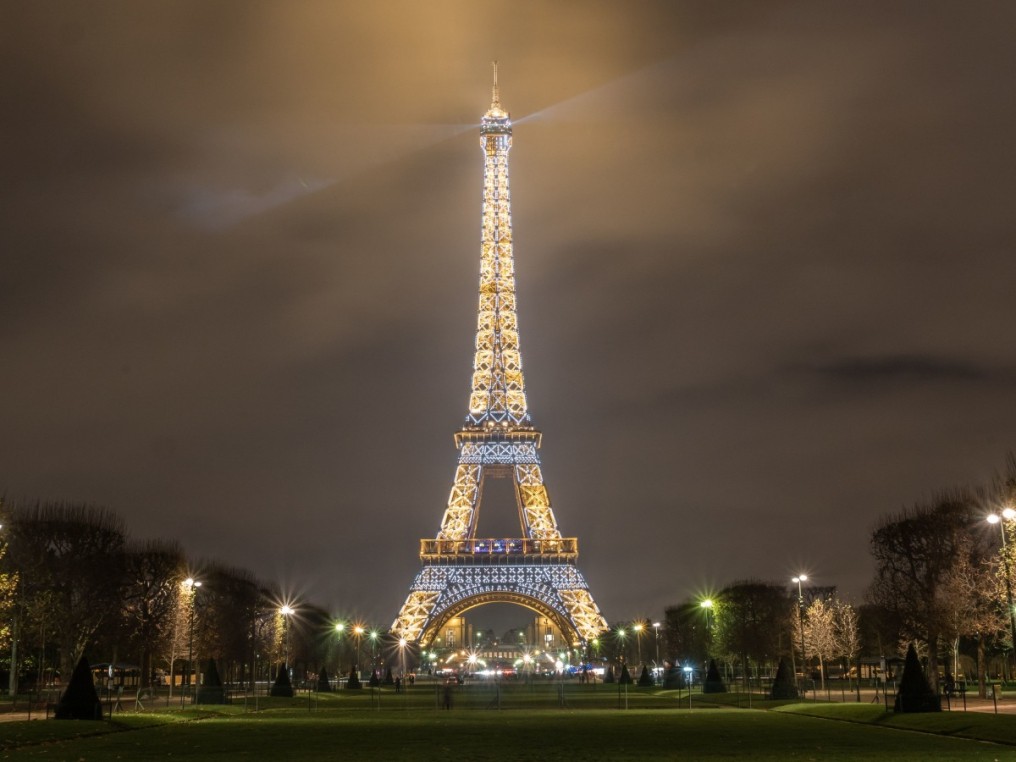 The illuminated Eiffel Tower seen from the Champ de Mars